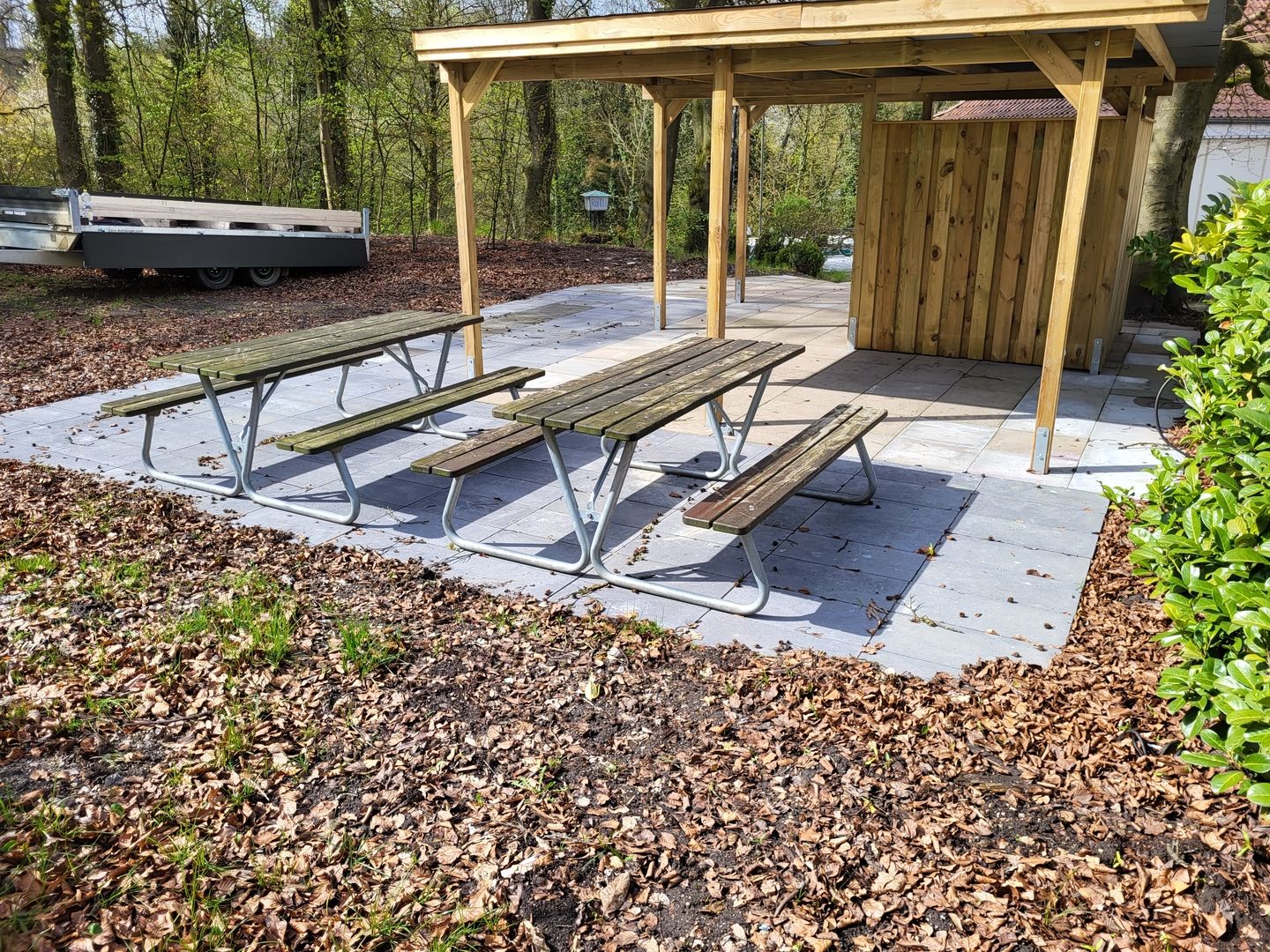 Eine Überdachung und davor stehen 2 Bänke und drumherum ist Wald.